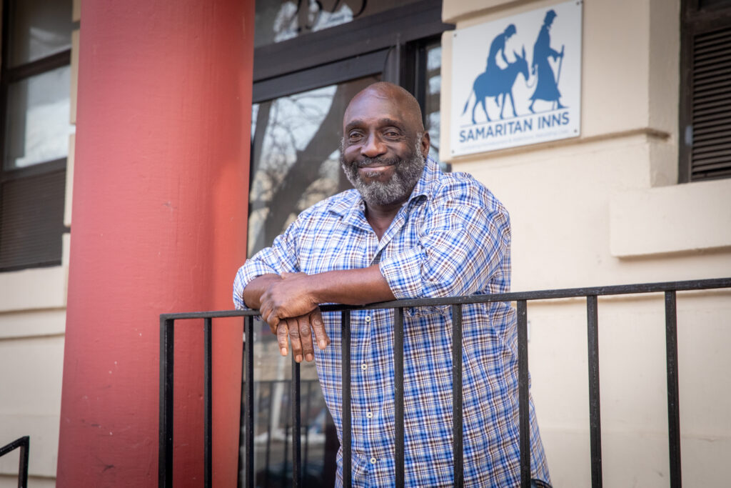 Smiling man standing on balcony leaning on railing